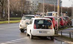 Biały Volkswagen Up i inne samochody stoją na pasach, blokując skrzyżowanie.