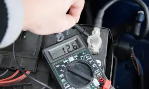 Pomiar napięcia multimetrem na akumulatorze samochodowym. Wynik 12.6V pokazuje, jak sprawdzić akumulator.