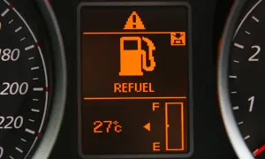 Na wyświetlaczu samochodu świeci się kontrolka paliwa z napisem "REFUEL" i ikoną dystrybutora. Wskaźnik pokazuje niski poziom paliwa, co oznacza, że niedługo trzeba będzie tankować. Warto sprawdzić, ile można przejechać na rezerwie.
