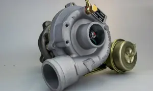 Metalowa turbosprężarka, potencjalnie z objawami uszkodzonej turbiny. Widoczny wirnik i zawór upustowy.