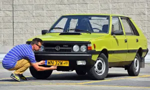 Mężczyzna przykręca żółtą rejestrację z oznaczeniem PL do polskiego samochodu FSO.