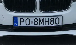 Białe tablice rejestracyjne e.g. PO 8MH80 na zderzaku samochodu.