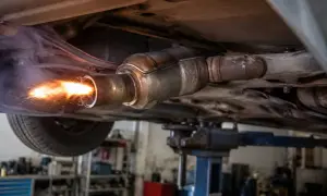 Intensywne płomienie i iskry wydobywające się z rury wydechowej samochodu na podnośniku. To może być proces wypalania DPF na postoju, który trwa różnie.