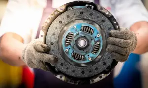Mechanik trzyma w rękawicach odwrotnie założoną tarczę sprzęgła, gotową do montażu.