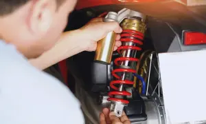Mechanik wymienia amortyzator w skuterze. Czas pracy: ile trwa wymiana amortyzatorów?