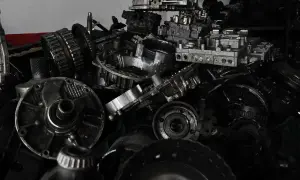 Stos części samochodowych, głównie elementów skrzyni biegów, czeka na utylizację.