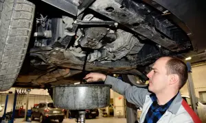Mechanik spuszcza olej z silnika. Pamiętaj, co ile wymiana oleju jest kluczowa dla żywotności auta.