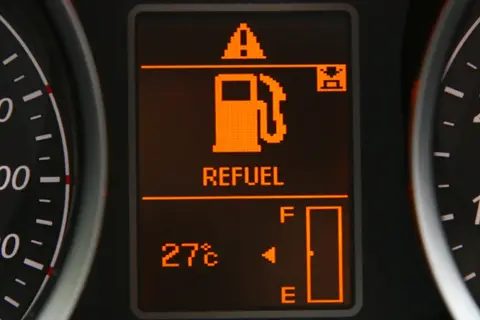 Na wyświetlaczu samochodu świeci się kontrolka paliwa z napisem "REFUEL" i ikoną dystrybutora. Wskaźnik pokazuje niski poziom paliwa, co oznacza, że niedługo trzeba będzie tankować. Warto sprawdzić, ile można przejechać na rezerwie.