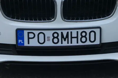 Białe tablice rejestracyjne e.g. PO 8MH80 na zderzaku samochodu.