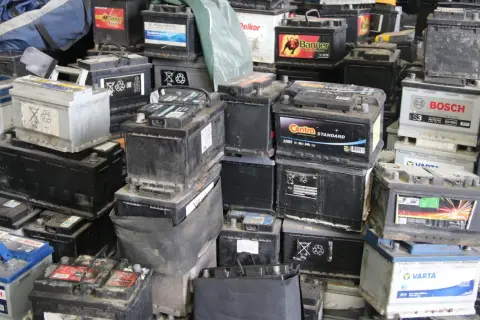 Stosy zużytych akumulatorów samochodowych, gotowych do recyklingu. Widać napisy marek jak Bosch, Varta, Centra. To miejsce, gdzie można oddać stary akumulator, a czasem nawet otrzymać zwrot kaucji za akumulator.