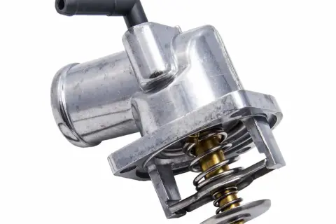 Metalowy termostat w samochodzie, kluczowy element układu chłodzenia, z widoczną sprężyną i zaworem.