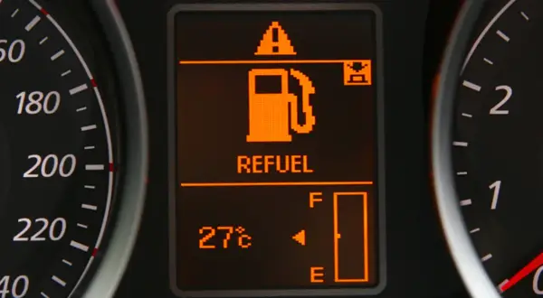 Na wyświetlaczu samochodu świeci się kontrolka paliwa z napisem "REFUEL" i ikoną dystrybutora. Wskaźnik pokazuje niski poziom paliwa, co oznacza, że niedługo trzeba będzie tankować. Warto sprawdzić, ile można przejechać na rezerwie.