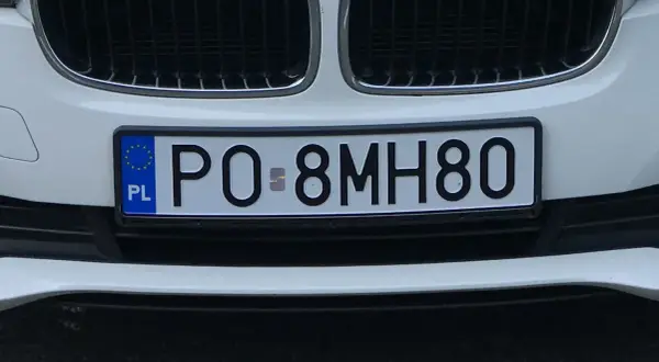 Białe tablice rejestracyjne e.g. PO 8MH80 na zderzaku samochodu.