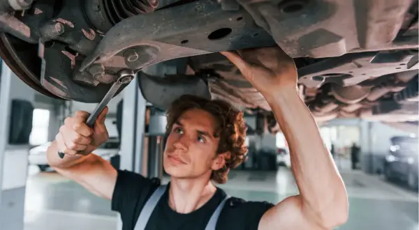 Mechanik naprawia zawieszenie, by uniknąć problemów z jazdą z uszkodzoną tuleją wahacza.