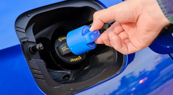Dłoń zdejmuje niebieską zakrętkę z napisem AdBlue. To płyn do redukcji emisji spalin w dieslach.