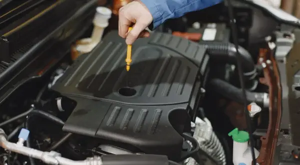 Mechanik sprawdza poziom oleju silnikowego. W tym miejscu zazwyczaj znajduje się bagnet, a nie wlew oleju do skrzyni biegów.