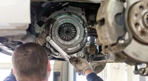 Mechanik dokręca śruby koła zamachowego. Czas pracy, ile trwa wymiana sprzęgła, zależy od modelu auta i doświadczenia.