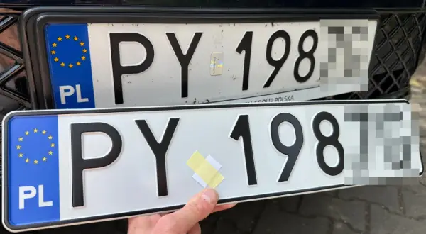Dwie polskie tablice rejestracyjne z numerem PY 198. Jedna jest zamontowana na samochodzie, druga trzymana w ręce.