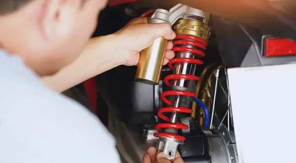 Mechanik wymienia amortyzator w skuterze. Czas pracy: ile trwa wymiana amortyzatorów?