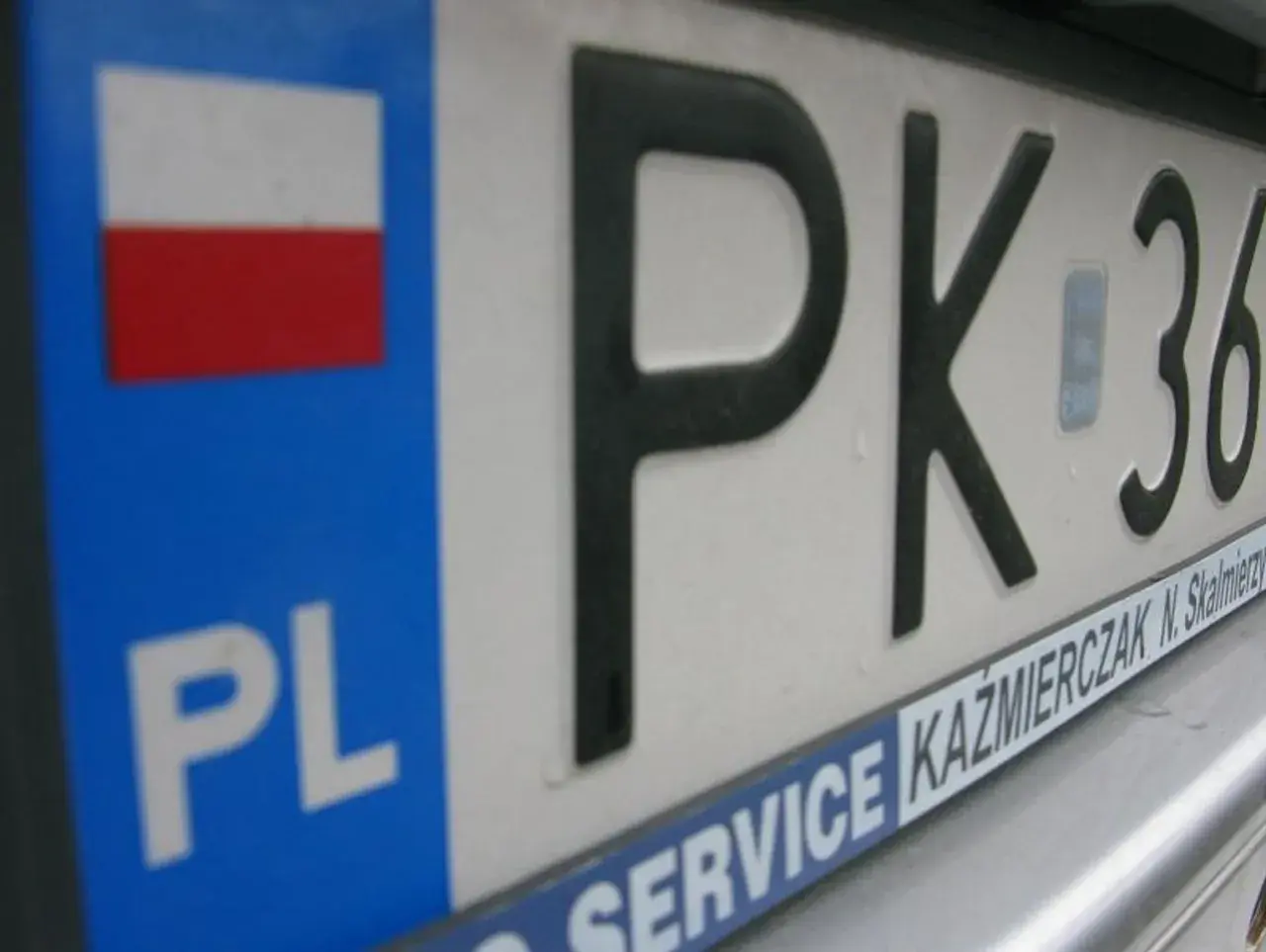 Zbliżenie na polską tablicę rejestracyjną z oznaczeniem PK. Widoczna flaga Polski i napis PL.