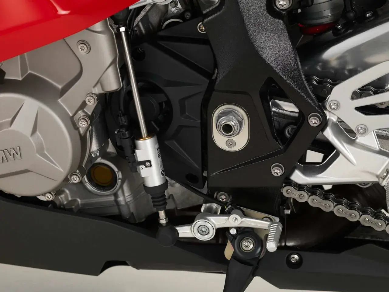 Mechanizm quickshifter co to? Widok na silnik motocykla BMW z elementami układu zmiany biegów, w tym siłownikiem quickshifter.