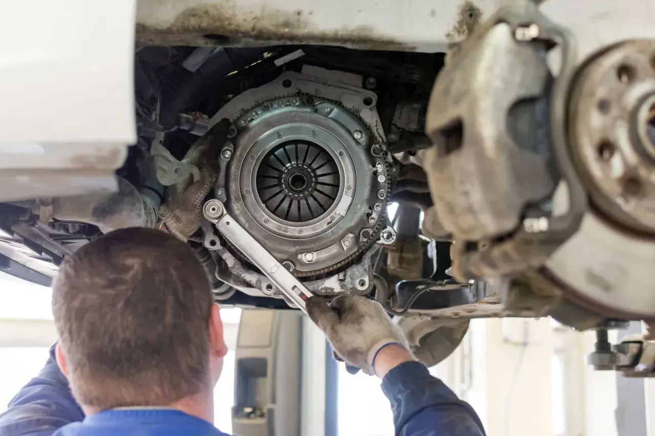 Mechanik dokręca śruby koła zamachowego. Czas pracy, ile trwa wymiana sprzęgła, zależy od modelu auta i doświadczenia.
