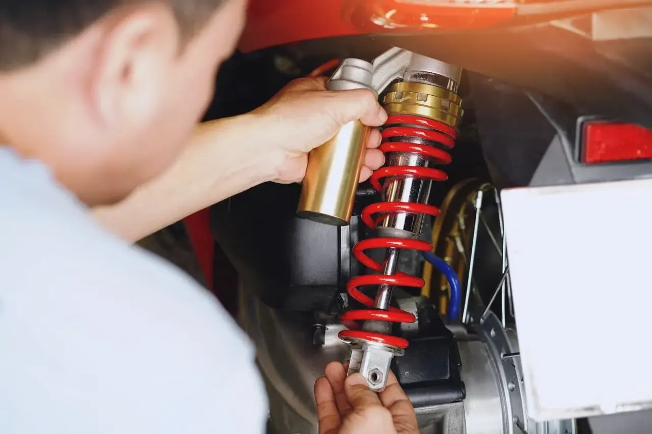 Mechanik wymienia amortyzator w skuterze. Czas pracy: ile trwa wymiana amortyzatorów?