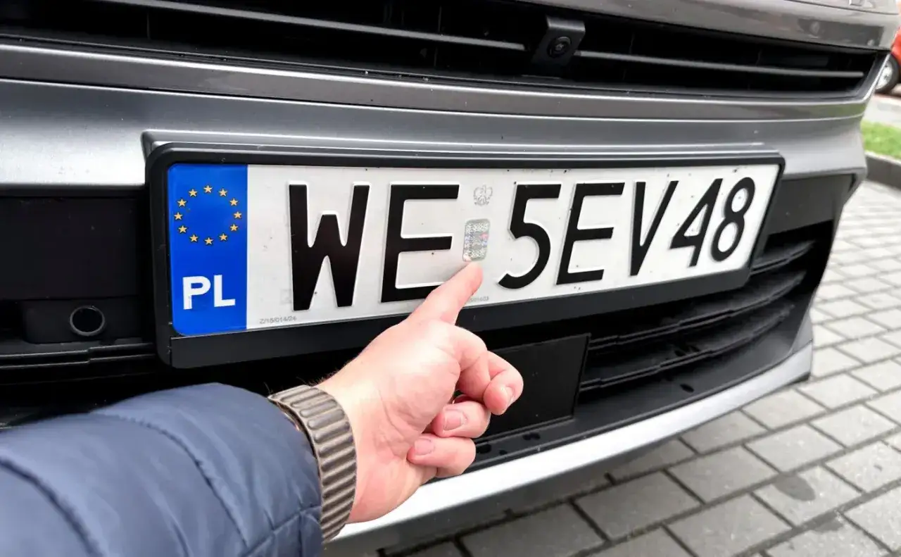 Palec wskazujący na hologram na polskich tablicach rejestracyjnych WE 5EV48.