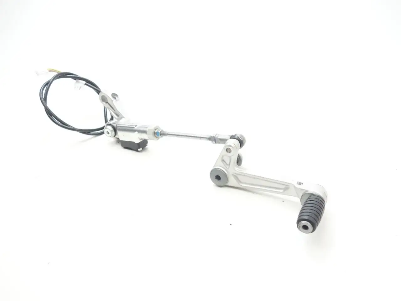 Mechanizm quickshifter co to? Metalowy element motocyklowej skrzyni biegów z czujnikiem i linką.