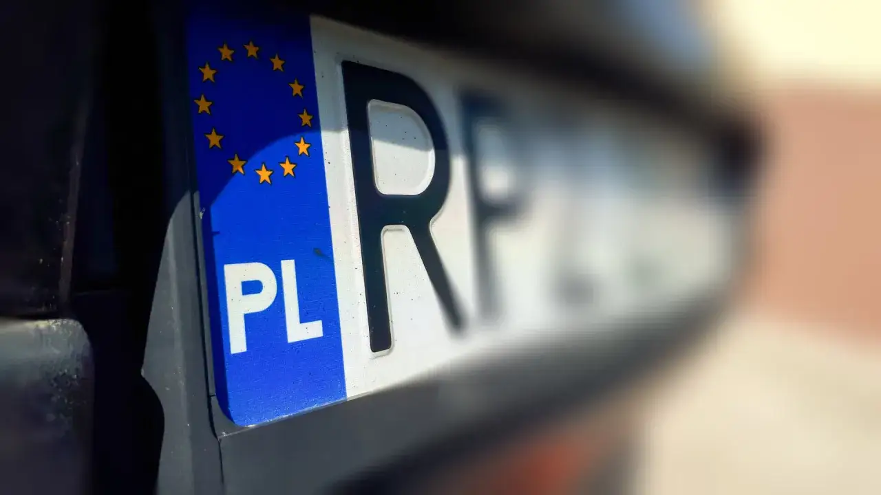 Zbliżenie na polską tablicę rejestracyjną z symbolem Unii Europejskiej. Litery 