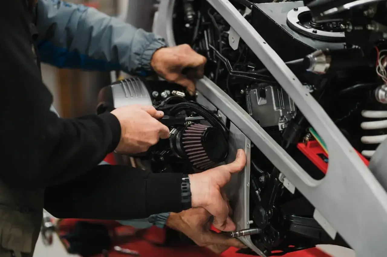 Mechanicy montują filtr paliwa w motocyklu. Upewniają się, że nie ma w nim wody, aby zapewnić płynną pracę silnika.