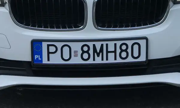 Białe tablice rejestracyjne e.g. PO 8MH80 na zderzaku samochodu.