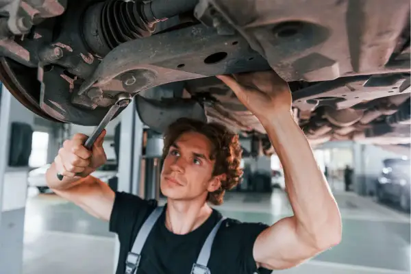 Mechanik naprawia zawieszenie, by uniknąć problemów z jazdą z uszkodzoną tuleją wahacza.